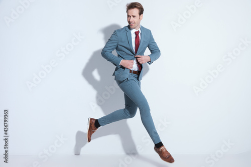 dynamic businessman jumping and unbuttoning blue suit