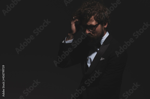 sexy businessman fixing his hair, wearing glasses and tuxedo