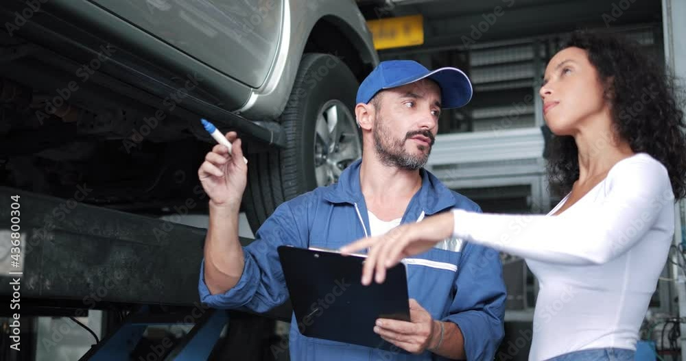 Vehicle technician mechanic having conversation with customer about car repairing budget cost and insurance. Woman listening to mechanic at maintenance garage service center workshop. Automotive