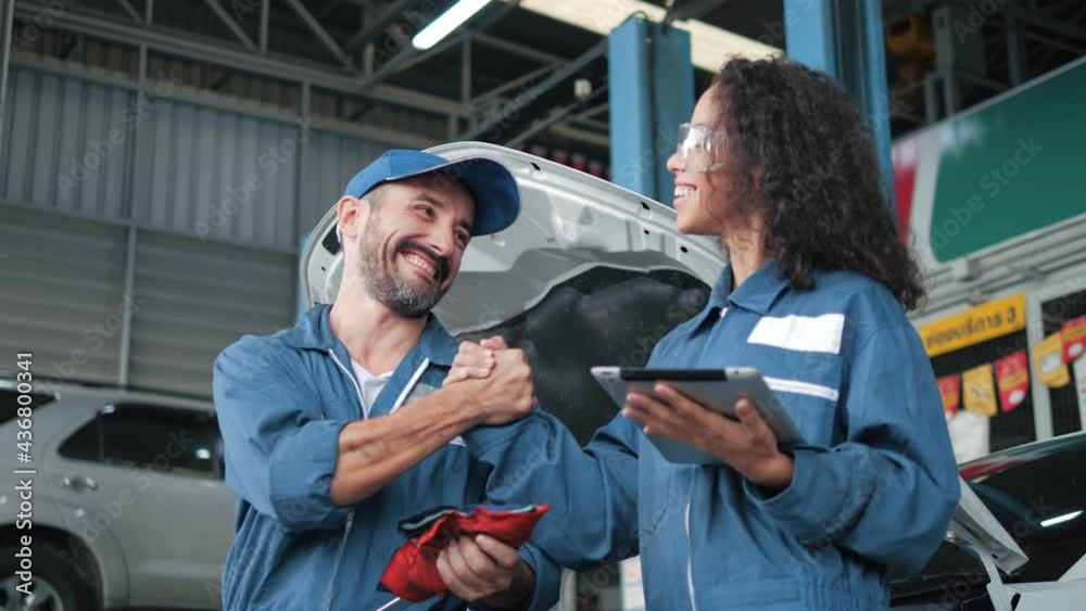 Two car mechanic team shaking hand at automobile service center. Repair service concept. Car repair and maintenance. Car mechanic working at automotive team service center.