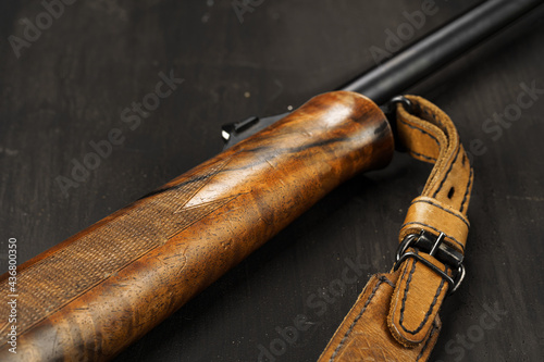 Wooden handle of hunting rifle on dark wooden background