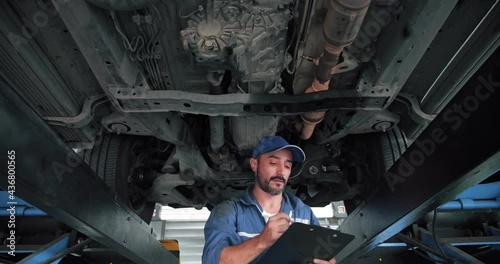Vehicle technician mechanic repairing suspension of a lifted car. Experience car service technician working at the garage.