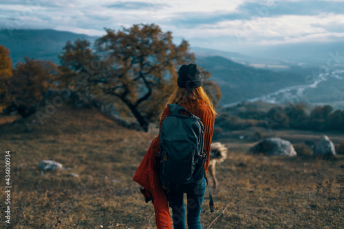 woman hiker with backpack on nature landscape dog