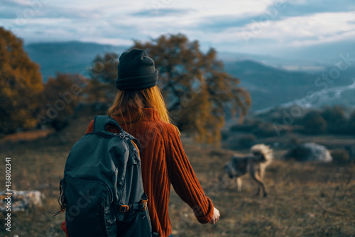 woman hiker with backpack on nature landscape dog