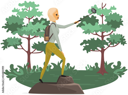 Climber reached summit of mountain. Traveling and technology concept. Lady with smartphone is posing for photo on background of forest. Woman taking selfie on mountain. Girl is traveling in nature