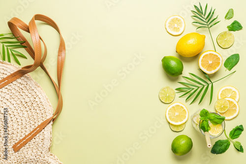 Summer pastel green background. Straw bag, lemon, lime, mint, lemonade. Top view, copy space