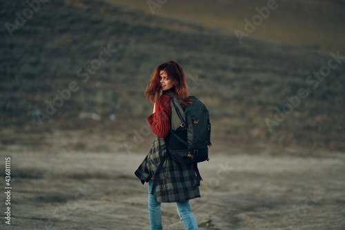 woman in a red sweater and jeans with a backpack on her back are resting in the mountains in nature
