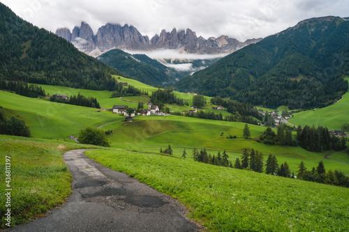 Hiking trail to St Magdalena church in Val di Funes valley, Dolomites, Italy. Furchetta and Sass Rigais mountain peaks in background