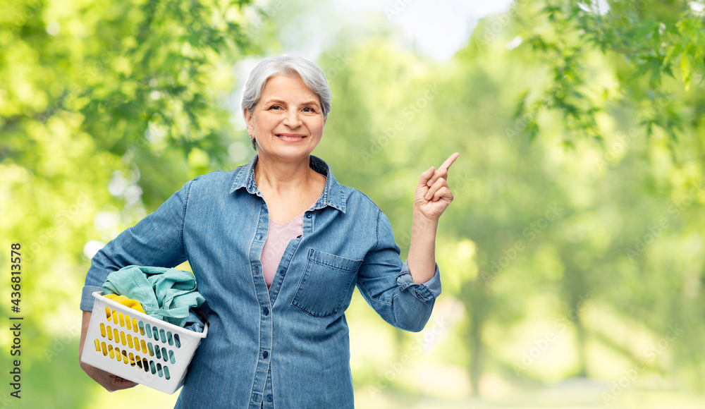 cleaning, wash and old people concept - portrait of smiling senior woman in denim shirt with laundry basket over green natural background cleaning, wash and old people concept - portrait of smiling senior woman in denim shirt with laundry basket over green natural background