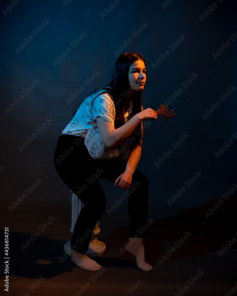 Girl on a stand on a dark background with multicolored light