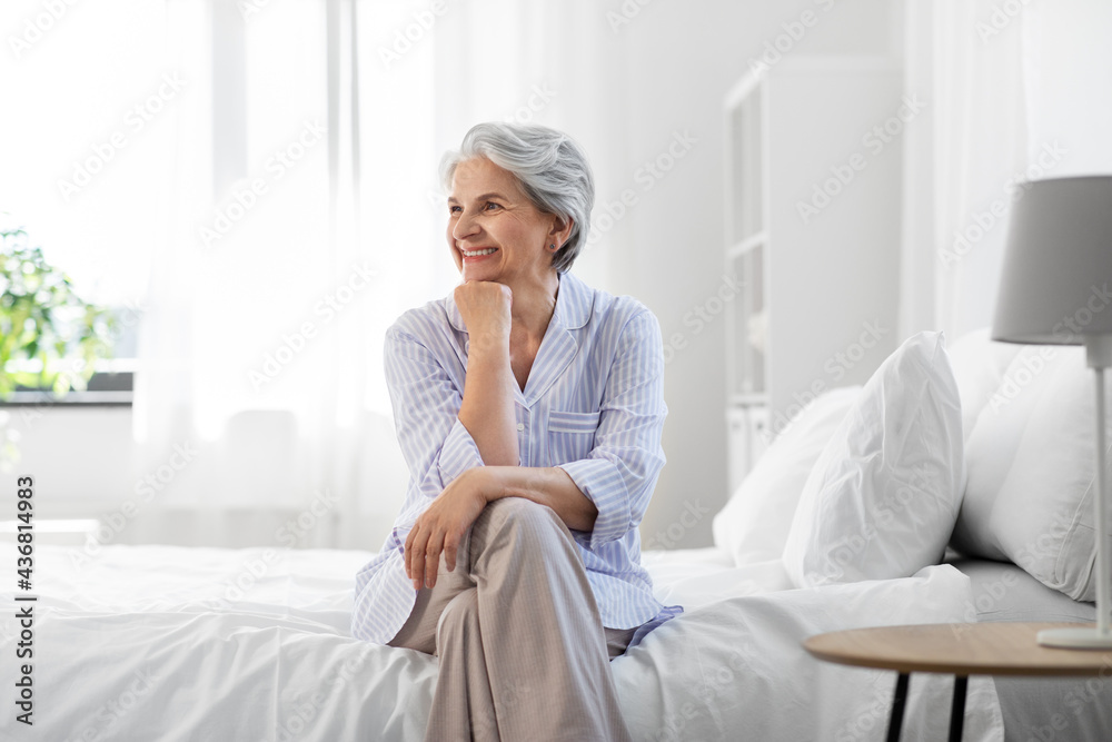 old age and people concept - happy smiling senior woman in pajamas sitting on bed at home bedroom old age and people concept - happy smiling senior woman in pajamas sitting on bed at home bedroom