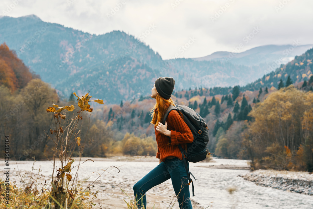 woman in a jeans sweater with a backpack rest in the mountains near the river in nature