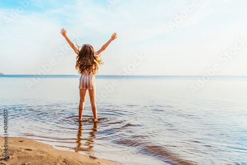 Little girl jumping on the beach in the water, the concept of a fun summer vacation