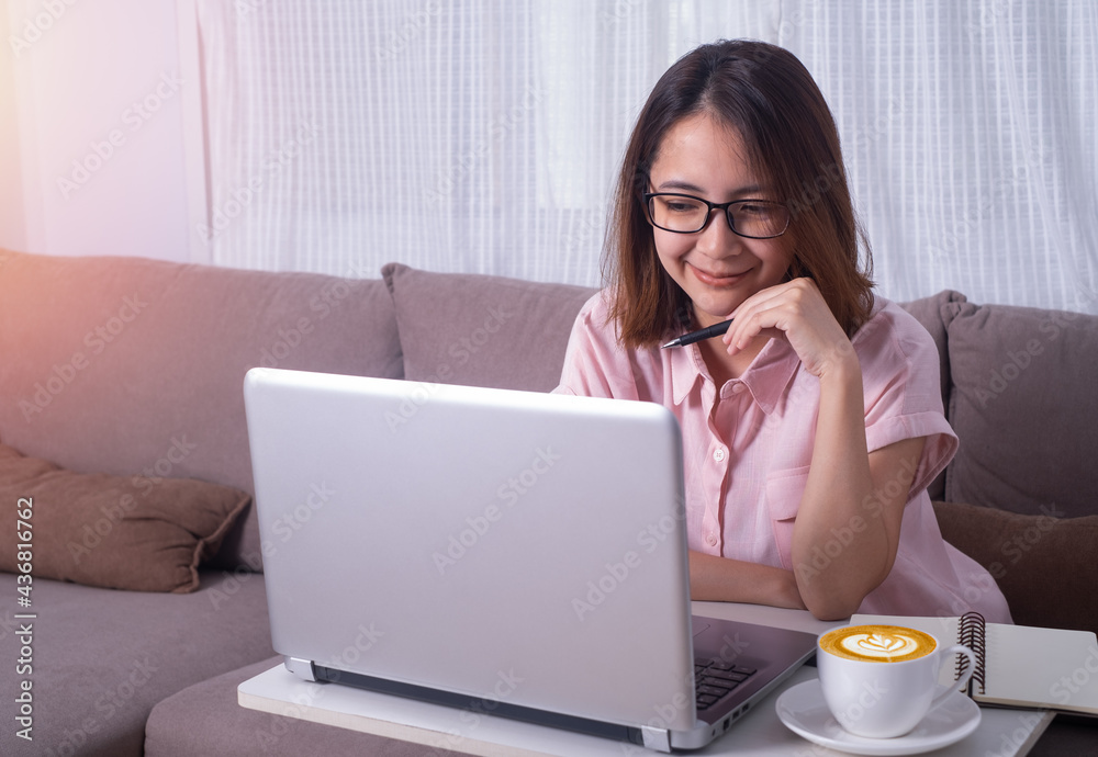 bussiness woman or student wearing glasses sitting on sofa in living room looking at the compoter notebook or laptop. Stay and Work from home and student study and learn online at home office concept. bussiness woman or student wearing glasses sitting on sofa in living room looking at the compoter notebook or laptop. Stay and Work from home and student study and learn online at home office concept.