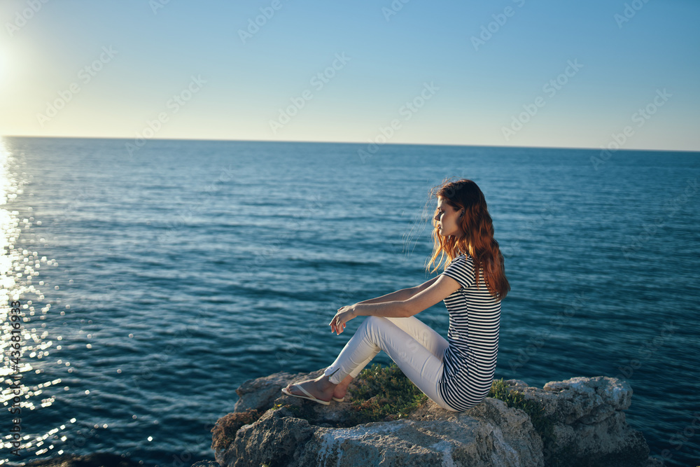 Naklejka premium the traveler sits on the beach near the sea in the mountains and sunset