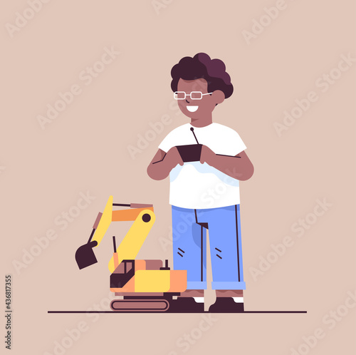 african american schoolboy playing with radio controlled tractor toy smiling boy having fun