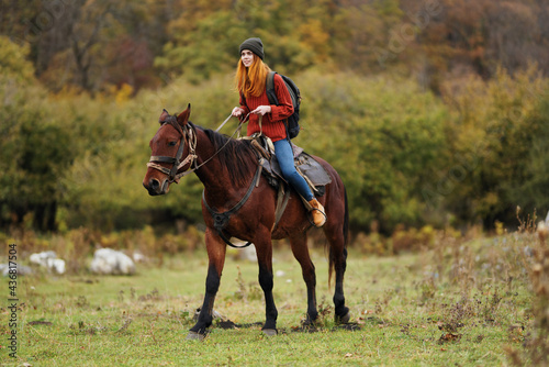 woman hiker with a backpack rides a horse in the mountains nature friendship