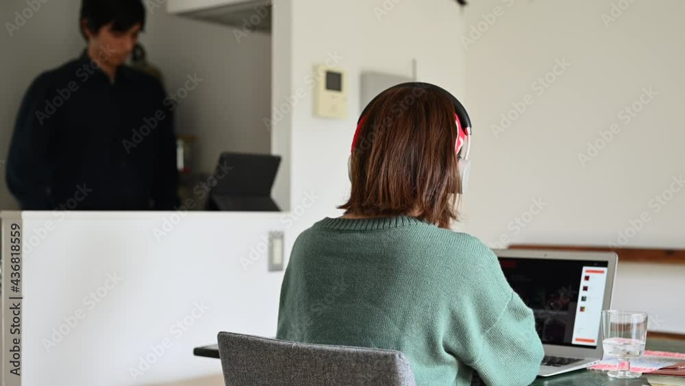 オンライン会議をする女性と、家事をする男性 オンライン会議をする女性と、家事をする男性