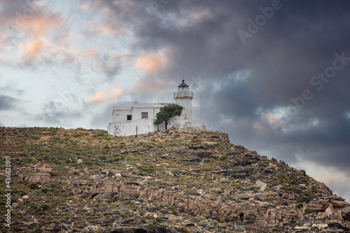 Kea island, Greece. Lighthouse Tamelos on a rocky cliff, cloudy sky background photo