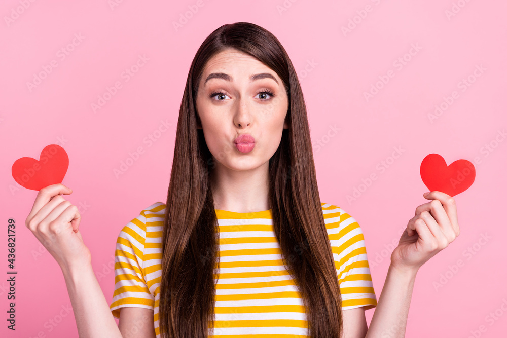 Photo of flirty young teenager lady hold hearts blow kiss wear orange t-shirt isolated on pink color background Photo of flirty young teenager lady hold hearts blow kiss wear orange t-shirt isolated on pink color background
