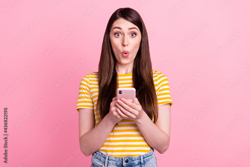 Photo of unexpected young lady hold telephone wear orange t-shirt isolated on pink color background Photo of unexpected young lady hold telephone wear orange t-shirt isolated on pink color background