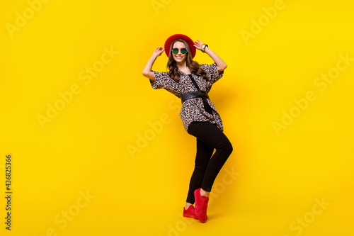 Full size photo of charming happy attractive young woman wear red hat shoes isolated on yellow color background