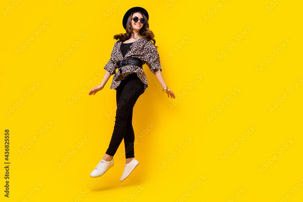 Full length photo of cheerful funky young woman look empty space jump up isolated on yellow color background