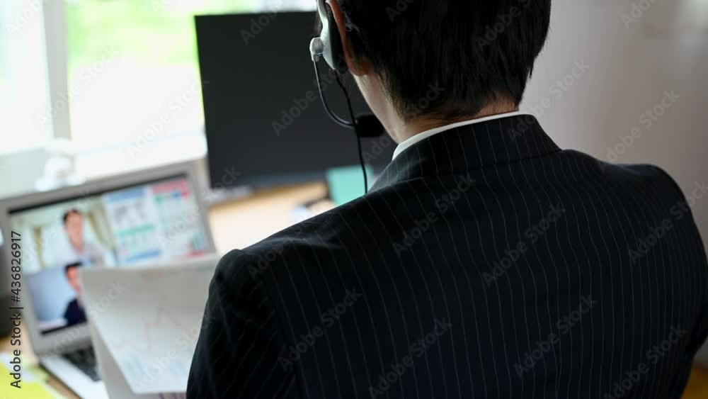家のデスクでテレカンファレンスに参加する男性社員 家のデスクでテレカンファレンスに参加する男性社員