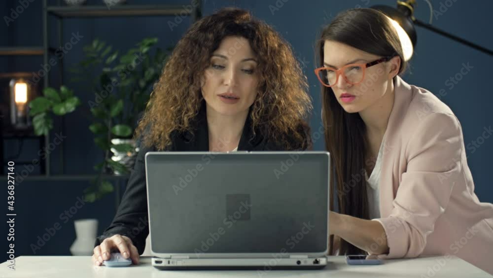 Focused female colleagues sit at desk in office brainstorm discuss business idea use laptop. Cooperation concept. Focused female colleagues sit at desk in office brainstorm discuss business idea use laptop. Cooperation concept.