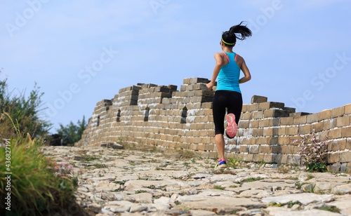 Woman runner athlete cross country running on great wall,China photo