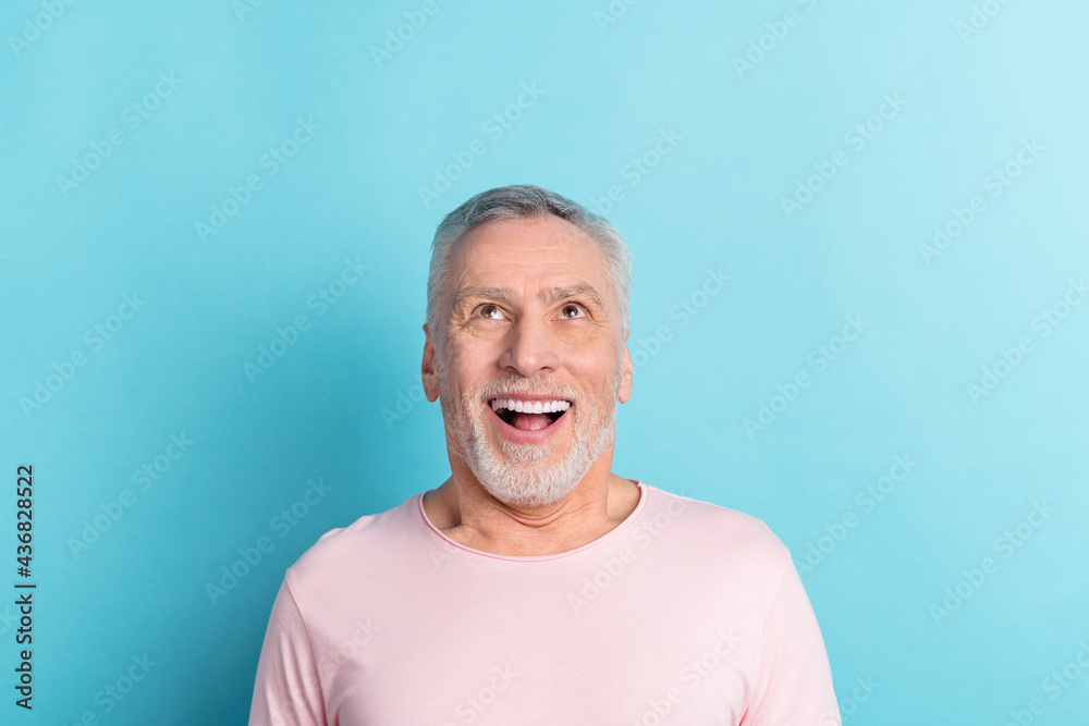 Photo portrait of bearded man pink t-shirt amazed looking up copyspace isolated on pastel blue color background Photo portrait of bearded man pink t-shirt amazed looking up copyspace isolated on pastel blue color background