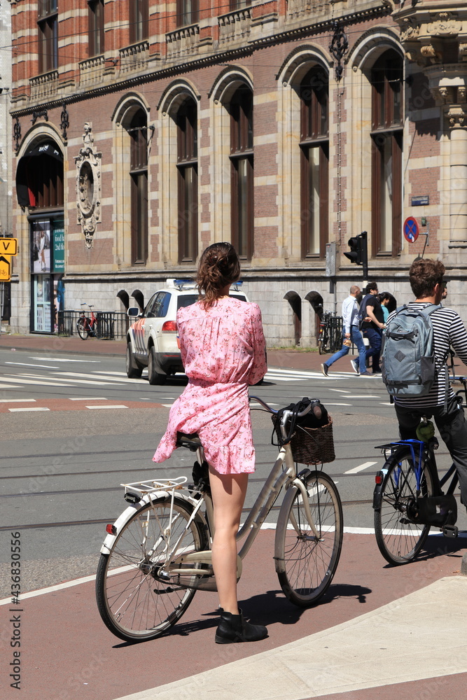 Amsterdam Street View with Woman in a Pink Dress on a White Bicycle