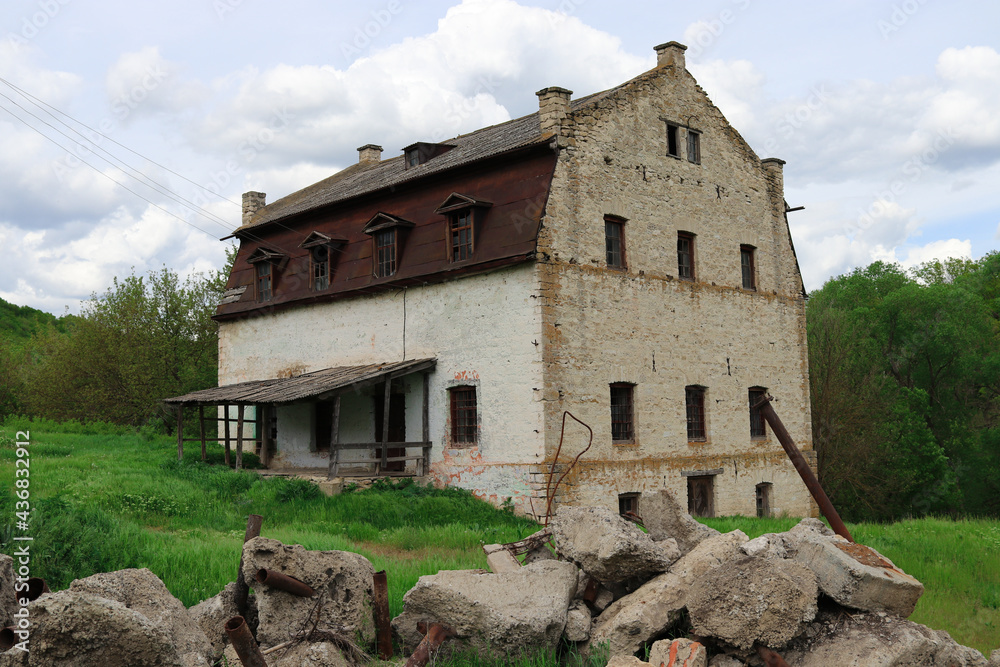 The building of an old abandoned mill of the 19th century on a green meadow near the stream The building of an old abandoned mill of the 19th century on a green meadow near the stream