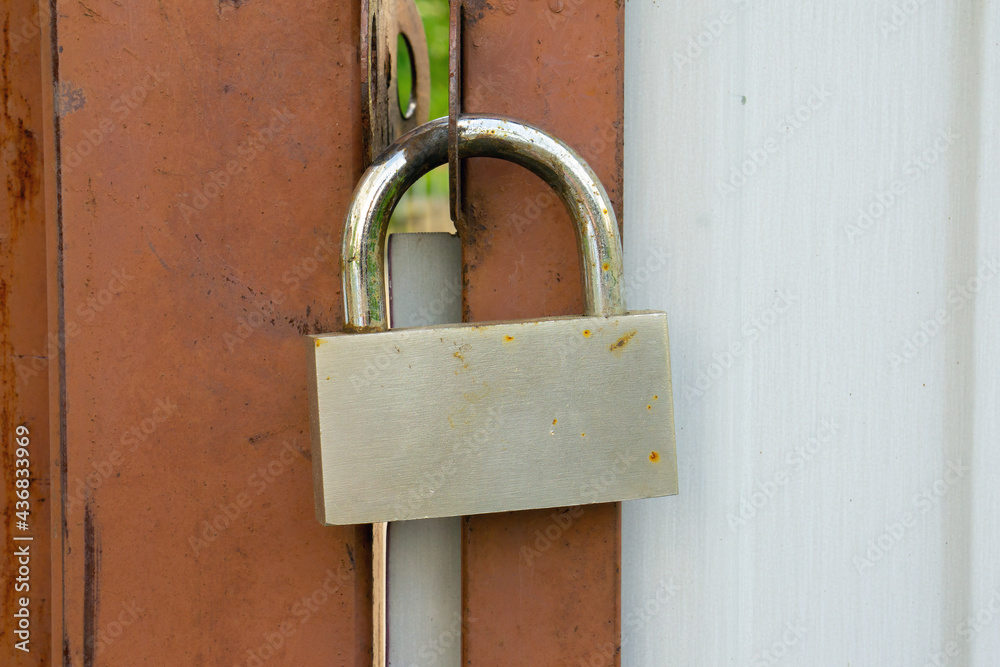 metal padlock on gray gate with rust close up front view metal padlock on gray gate with rust close up front view