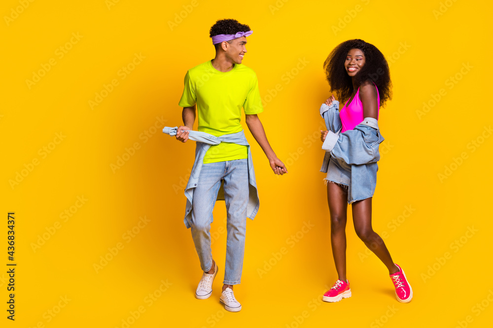 Fototapeta premium Photo of beautiful funky young couple dressed denim outfit dancing isolated yellow color background