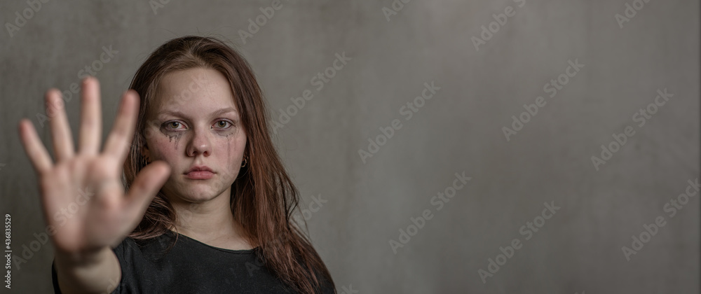 Unhappy teenage girl shows a stop sign with her hand. Empty space for text