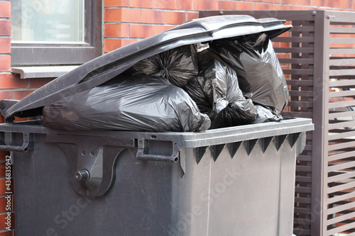 black plastic trash can filled with garbage bags