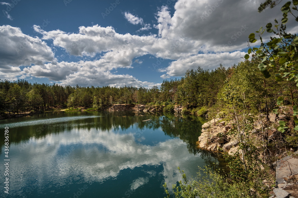 Lake in the forest, with a reflection of the sky and clouds