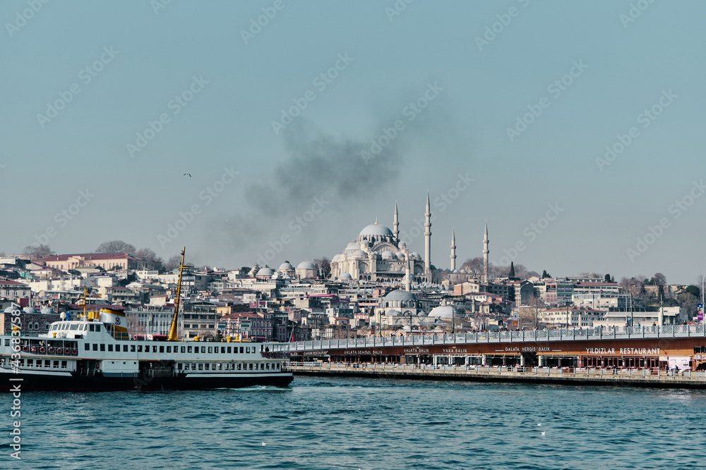 Turkey istanbul 03.03.2021. Old and ottoman yeni Cami mosque in istanbul turkey during morning with ancient galata bridge pedestrian ferry in golden horn.