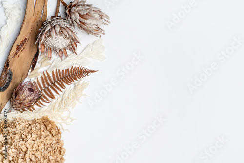 Rustic dried flower arrangement of pink King Protea, white Ruscus, orange Hydrangea, cream Amaranthus, rust fern leaf and decorative bark. Photographed from above, on a white background. photo
