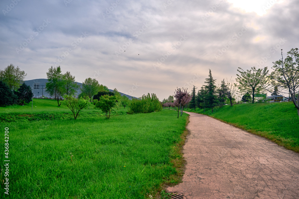 Natural public park in bursa during sunset with gravel and walking path around the green grass with ulu mountain (uludag) background in center of the city.