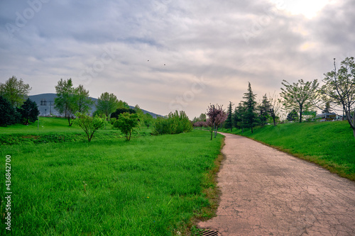 Natural public park in bursa during sunset with gravel and walking path around the green grass with ulu mountain (uludag) background in center of the city.