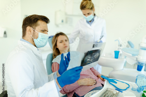 Male dentist is explaining x-ray pictures to patient. Patient and doctor discuss about x-ray picture