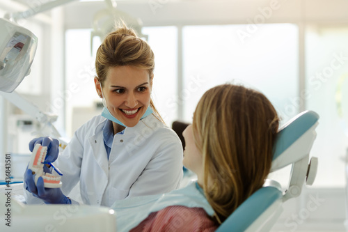 Female beautiful dentist is showing to patient how to brush teeth properly.