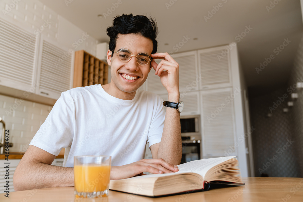 Young hispanic man reading a book while having breakfast Young hispanic man reading a book while having breakfast