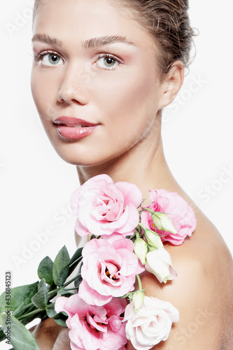 Portrait of a beautiful young woman with clean skin  soft day makeup and pink flowers  beauty treatment  cosmetology and anti-aging theme