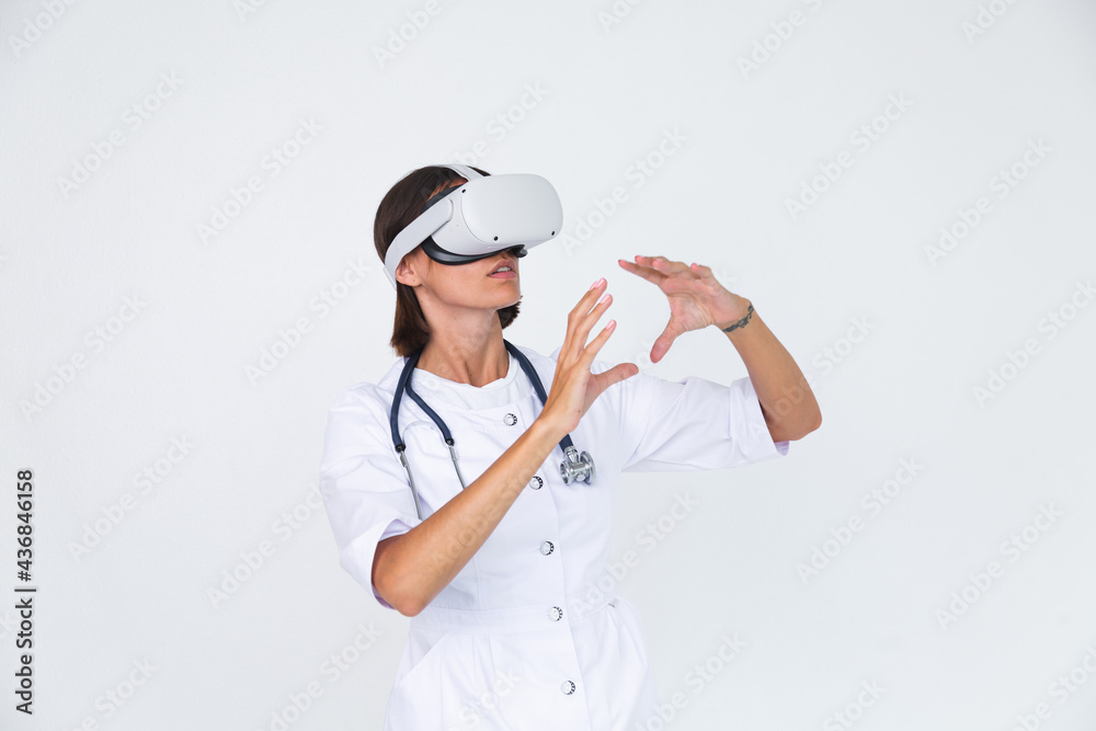 Female doctor in lab coat on white background isolated, wearing virtual reality glasses touch air Female doctor in lab coat on white background isolated, wearing virtual reality glasses touch air