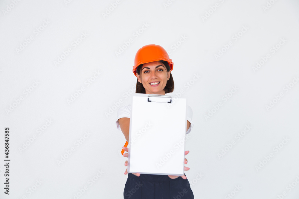 Pretty woman engineer in building protective helmet on white background smile hold white paper blank with empty space Pretty woman engineer in building protective helmet on white background smile hold white paper blank with empty space