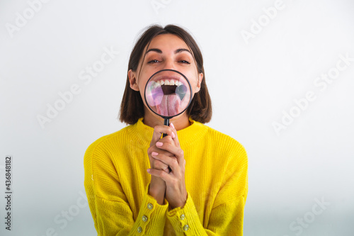 Pretty woman in yellow sweater on white background held magnifier happy positive playful funny tongue out mouth