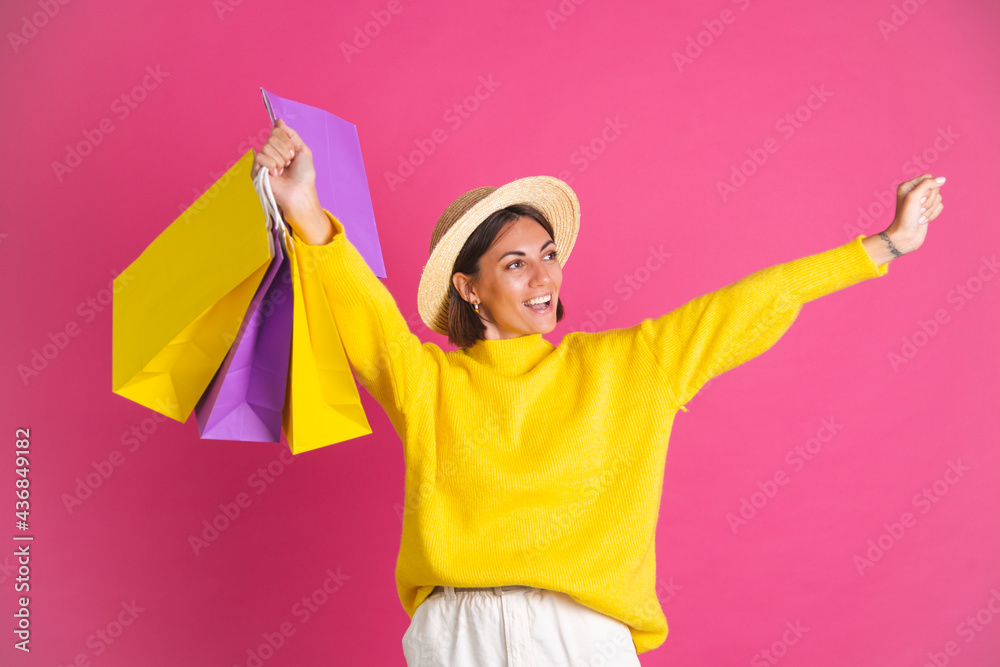Beautiful woman in bright yellow sweater and straw hat on pink background hold shopping bags happy excited joyful isolated space for text